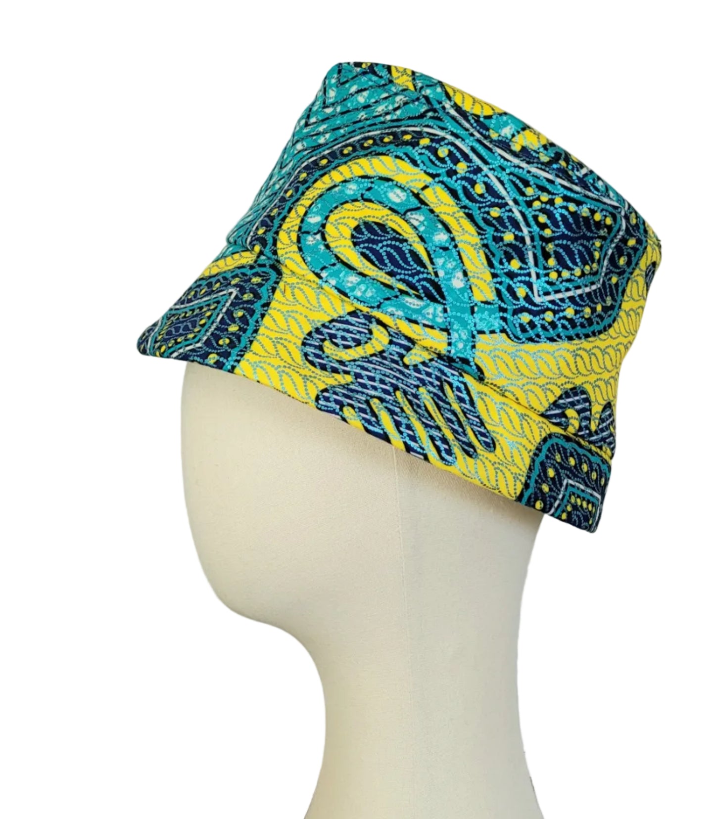 Teal, yellow and blue patterned fabric hat displayed on a cream mannequin head against a plain white wall and dark floor.