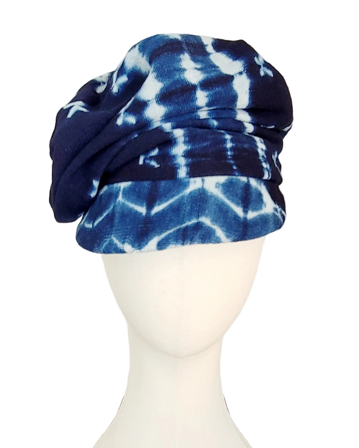 A blue and white tie-dye fabric hat displayed on a white mannequin head against a plain white background.