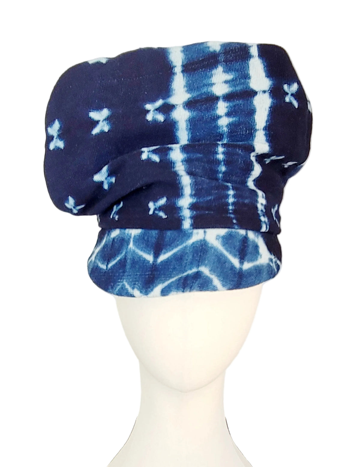 A blue and white tie-dye flat cap displayed on a white mannequin head against a white background.